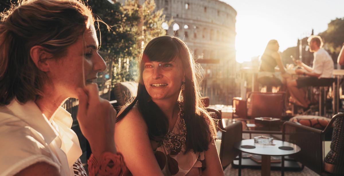 Due turiste bevono aperitivo al tramonto davanti al Colosseo - Foto di ronnybas da Adobe Stock