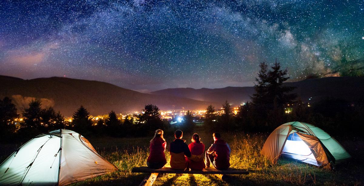 Giovani siedono fuori le tende sotto un cielo stellato - Foto di anatoliy_gleb da Adobe Stock