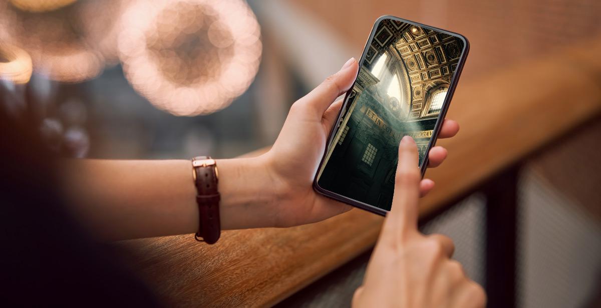 Ragazza osserva un particolare della Basilica di San Pietro sullo smartphone