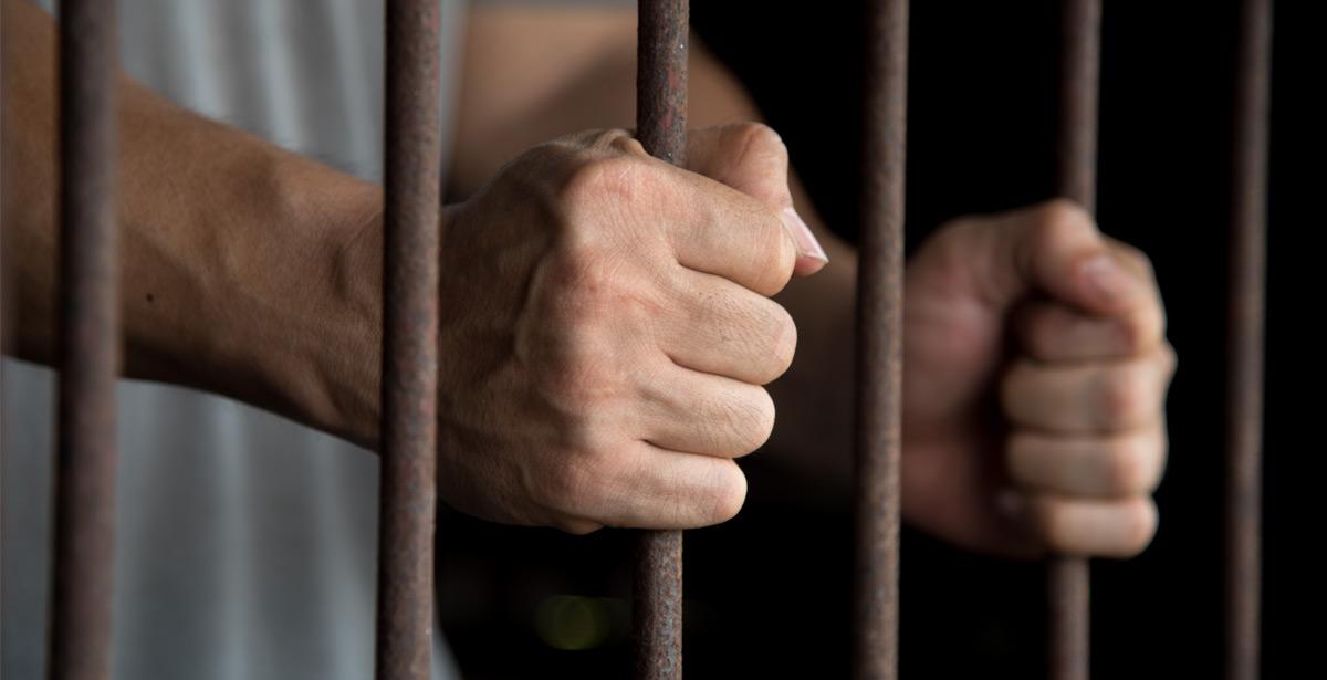 Mani di detenuto alle sbarre - Foto di kwanchaift da Adobe Stock