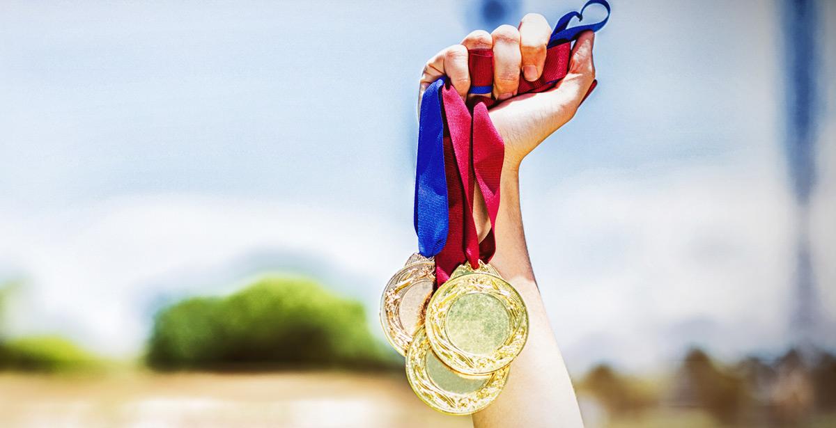 Mano femminile con medaglie sportive - Foto di vectorfusionart da Adobe Stock