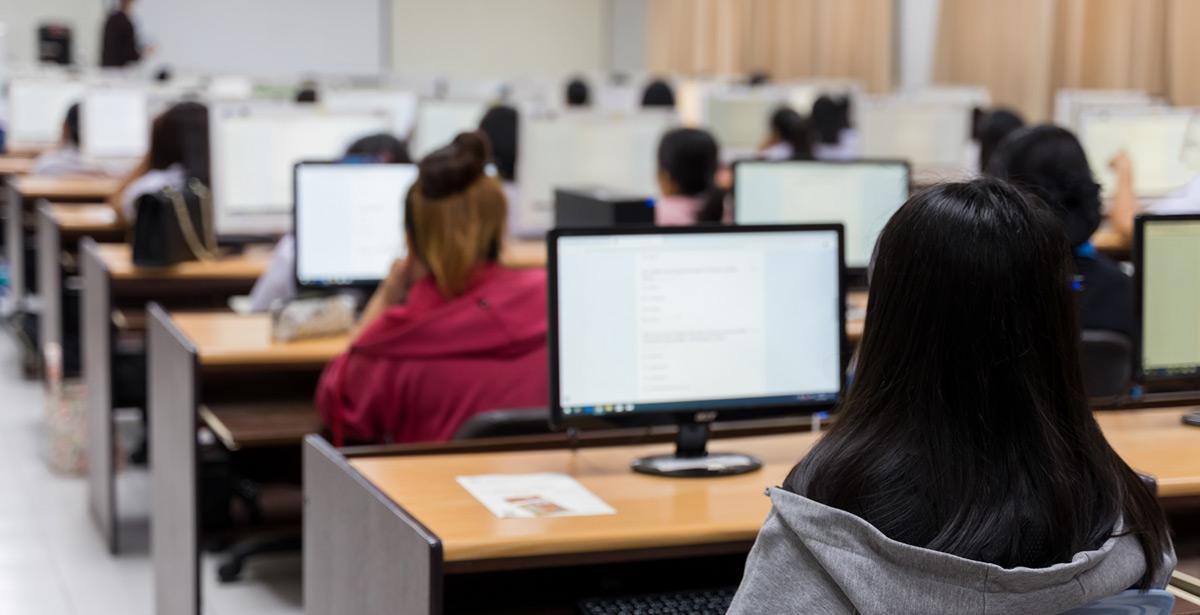 Studenti impegnati al pc in aula - Foto di Sengchoy Int da Adobe Stock