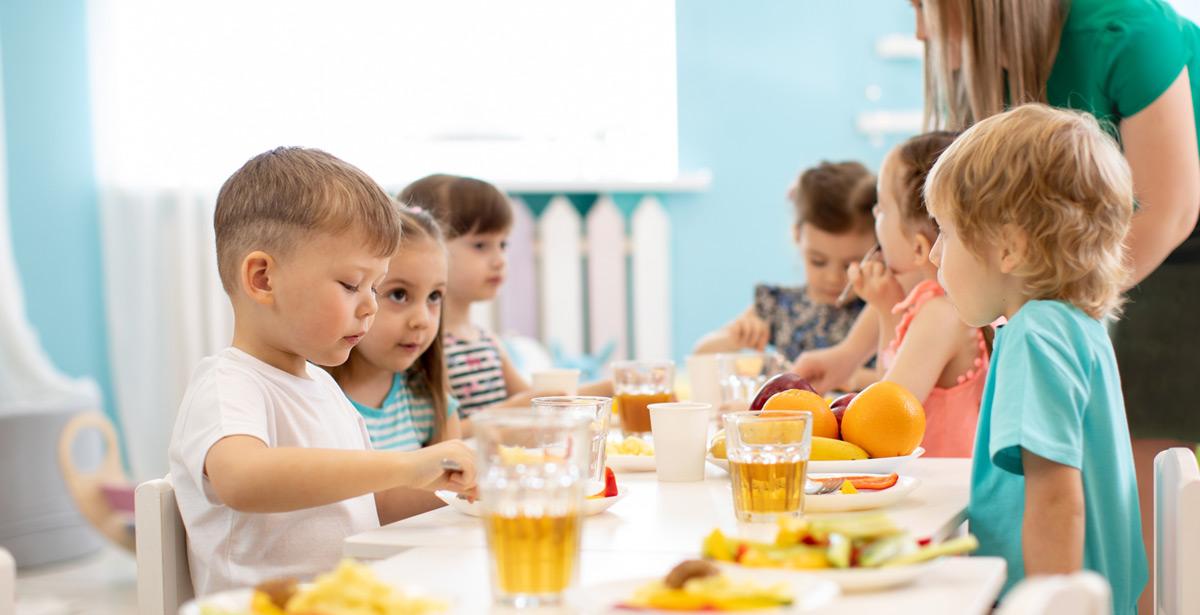 Bambini a pranzo in asilo con la maestra - Foto di Oksana Kuzmina da Adobe Stock