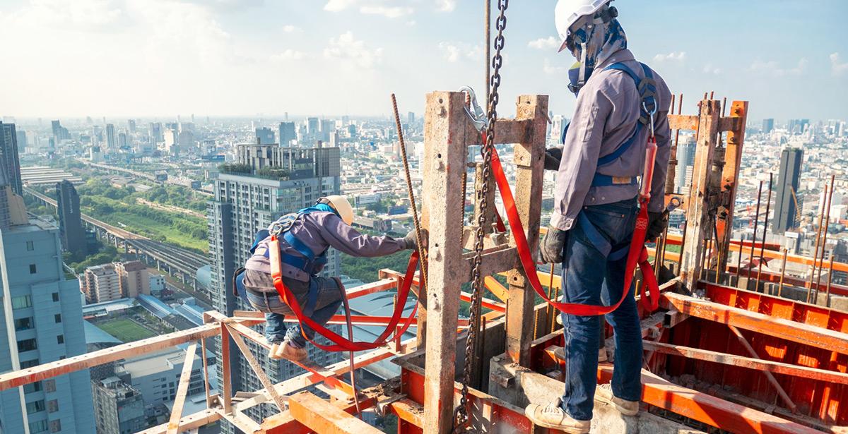 Operai lavorano in cima ad un palazzo con protezioni - Foto di bannafarsai da Adobe Stock