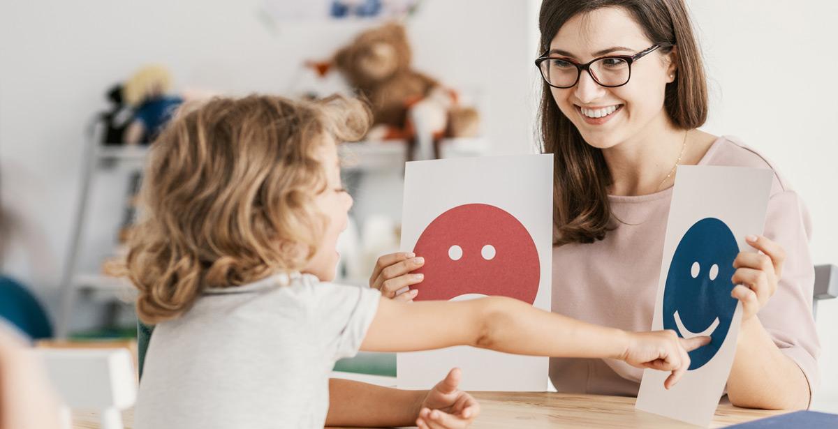 Educatrice aiuta una bambina con l'uso di emoticon - Foto di Photographee.eu da Adobe Stock