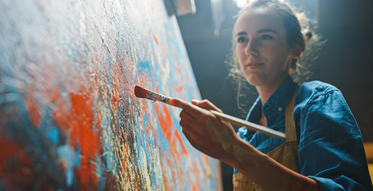 Primo piano di una giovane pittrice al lavoro sulla sua tela - Foto di Gorodenkoff da Adobe Stock