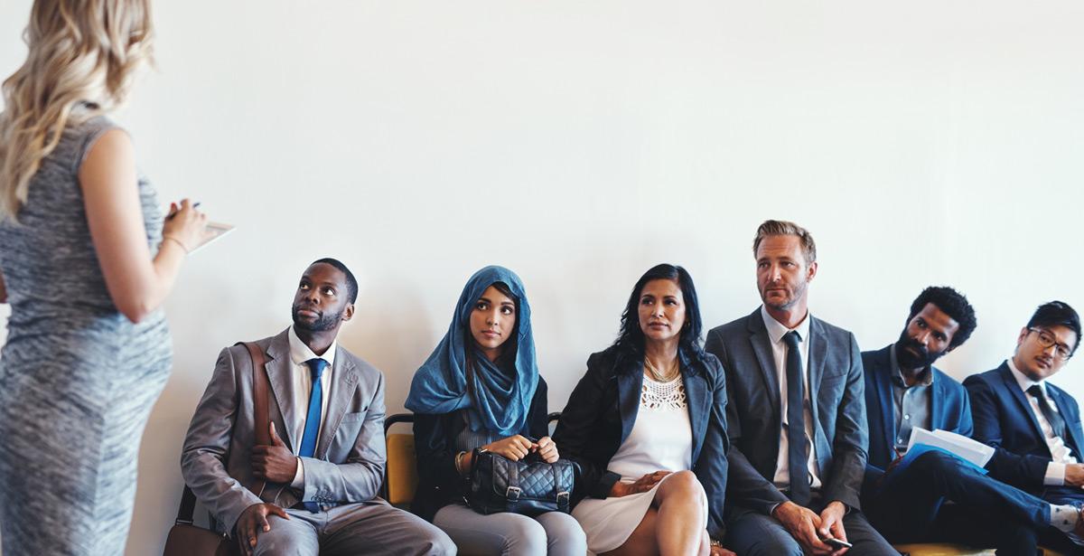 Impiegata parla con delle persone in attesa in un ufficio di collocamento - Foto di peopleimages.com da Adobe stock