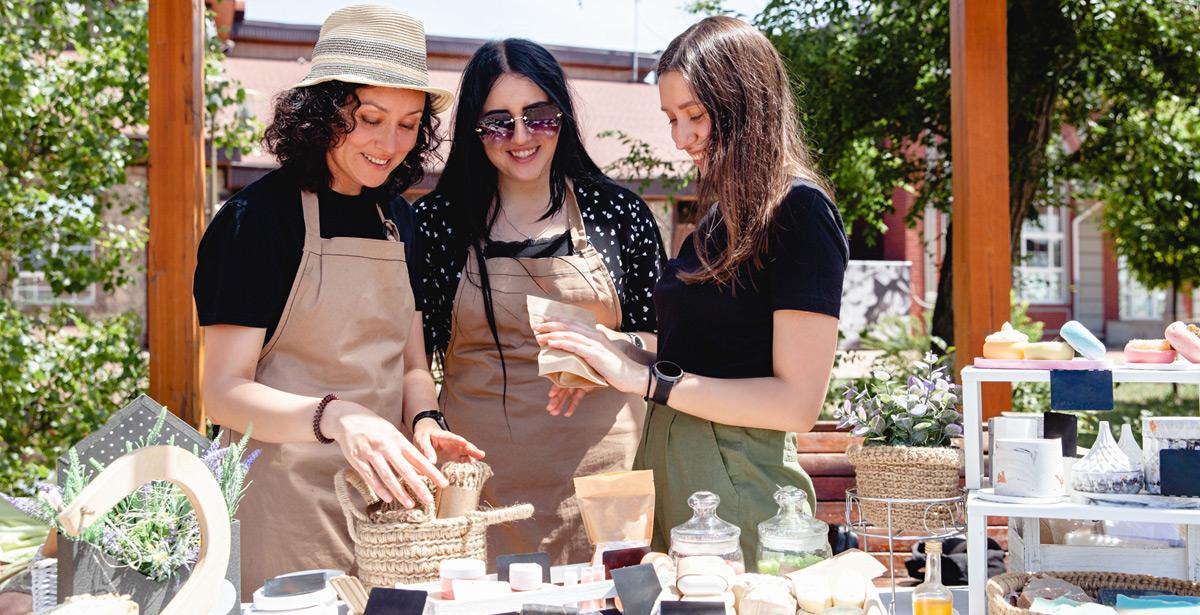 Tre giovani ragazze nel loro stand ad una fiera - Foto di Марина Десятниченко da Adobe Stock