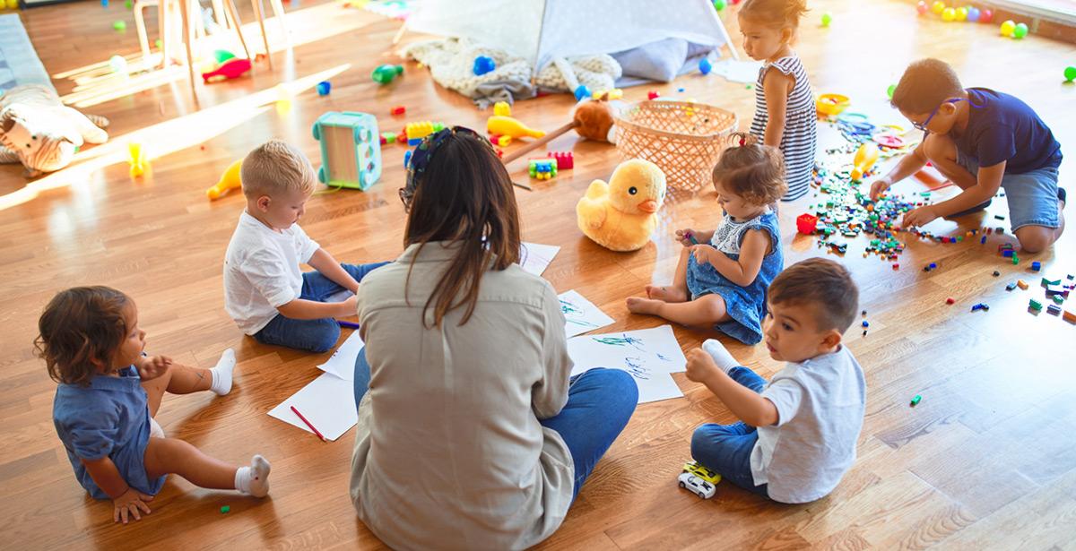 Bambini giocano in un asilo nido con l'educatrice - Foto di Krakenimages.com da Adobe Stock