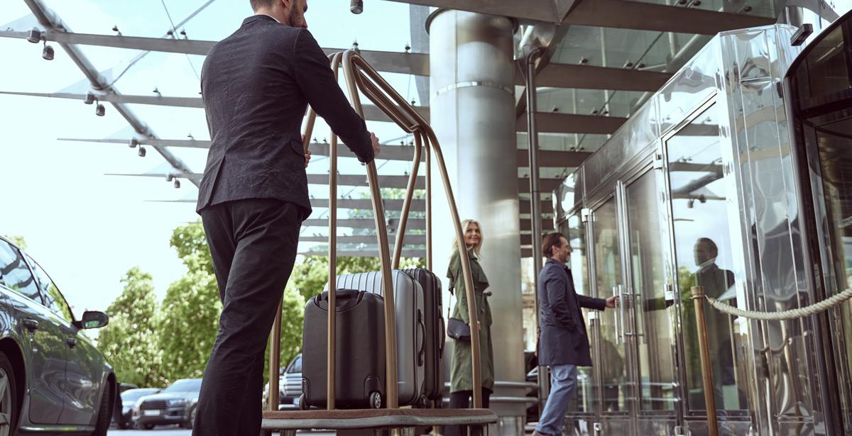 Facchino con valigie accompagna coppia dentro hotel - Foto di Yakobchuk Olena da Adobe Stock