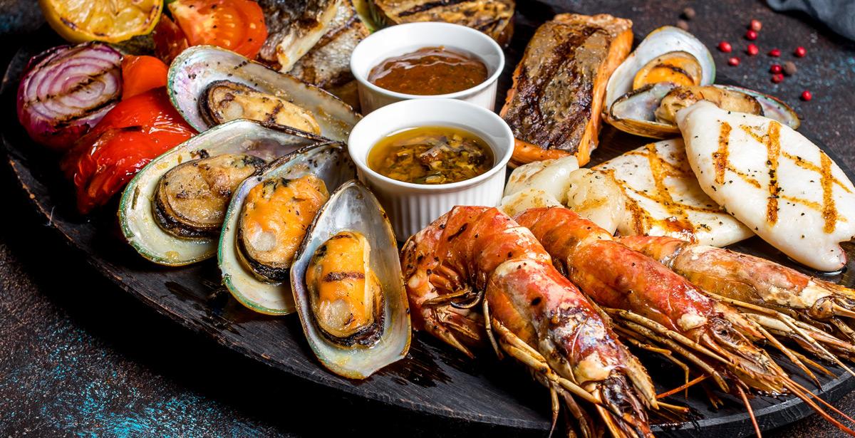 Piatto di frutti di mare, crostacei, verdure e salse - Foto di bbivirys da Adobe Stock