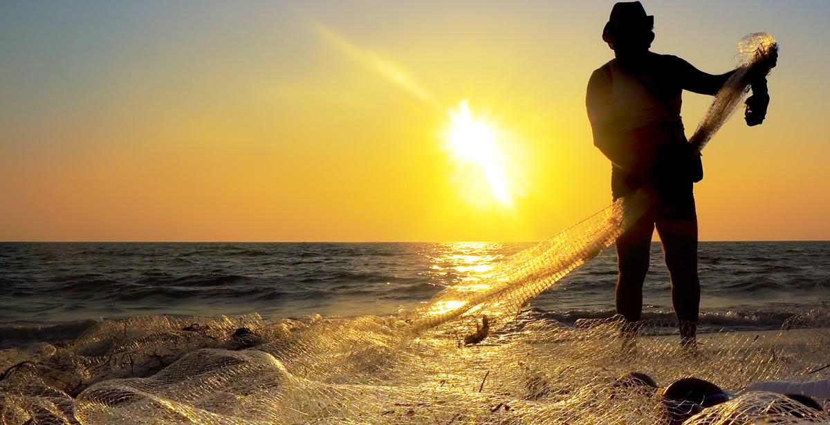 Pescatore lavora sulle reti al tramonto - Foto di zefart da Adobe Stock