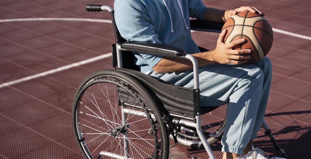 Ragazzo disabile su sedia a rotelle con pallone da basket in mano
