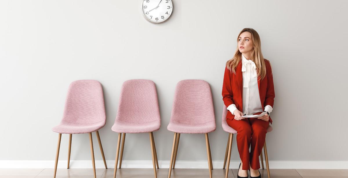 Ragazza attende seduta con orologio a muro in vista - Foto di Pixel-Shot da Adobe Stock